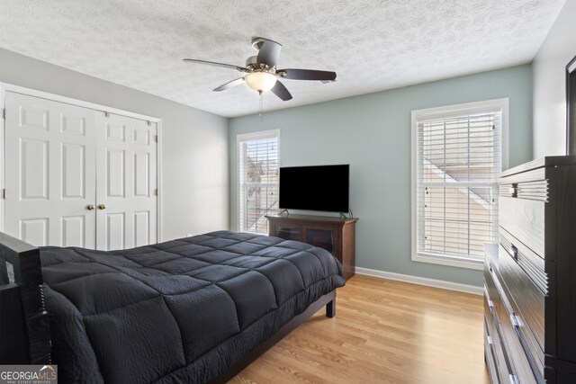 bedroom featuring light wood finished floors, a closet, a textured ceiling, and baseboards