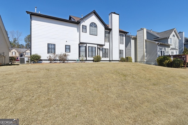 back of house with a yard, central AC, and a chimney