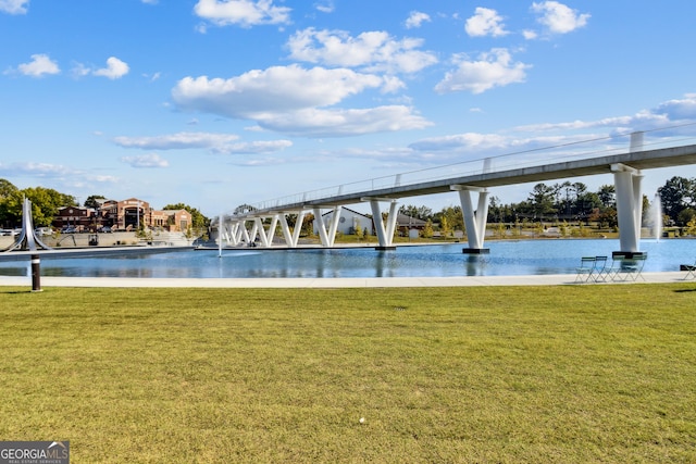 view of pool with a yard and a water view