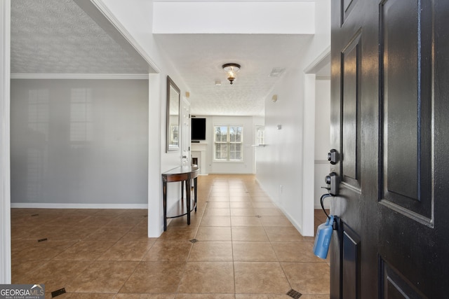 tiled entryway with visible vents, baseboards, a textured ceiling, and a fireplace