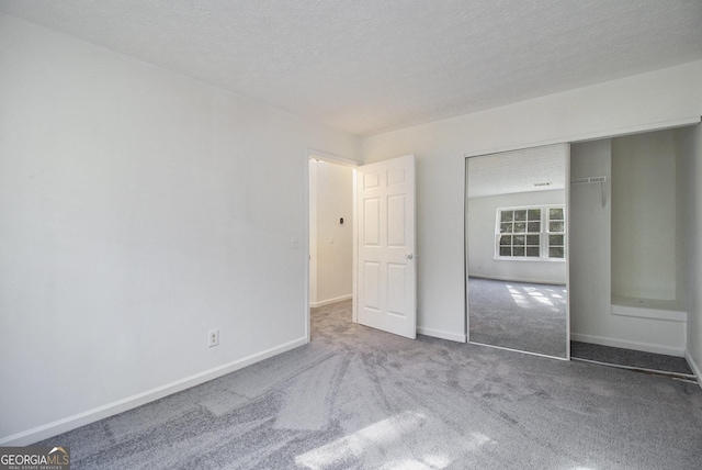 unfurnished bedroom with a closet, baseboards, a textured ceiling, and carpet flooring