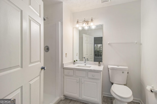 full bathroom featuring vanity, wood finished floors, walk in shower, a textured ceiling, and toilet