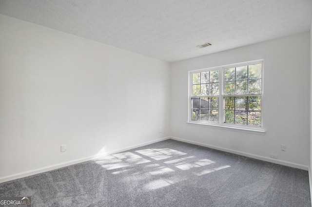 spare room featuring visible vents, baseboards, carpet, and a textured ceiling