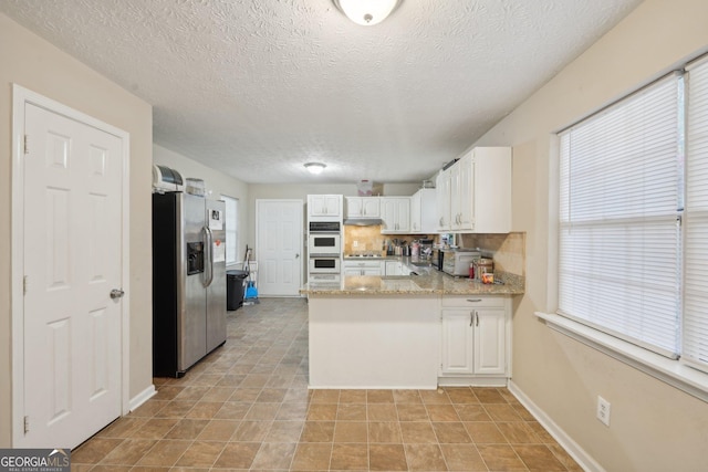 kitchen featuring a peninsula, white cabinets, stainless steel refrigerator with ice dispenser, and a wealth of natural light