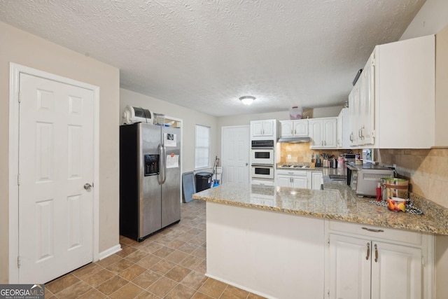 kitchen featuring tasteful backsplash, stainless steel fridge with ice dispenser, double oven, a peninsula, and white cabinetry