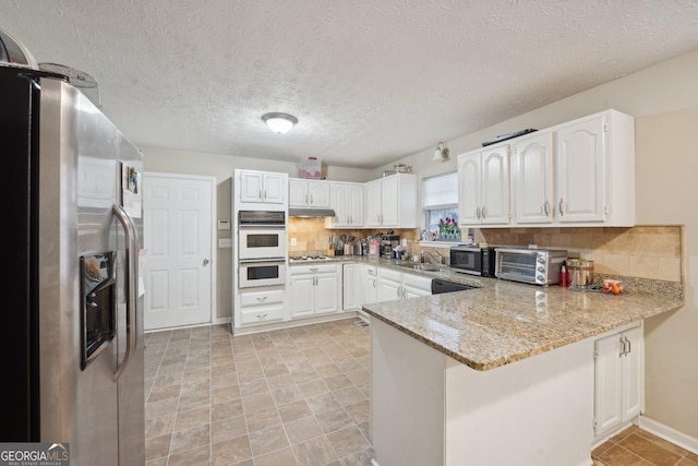 kitchen featuring tasteful backsplash, appliances with stainless steel finishes, a peninsula, white cabinets, and a toaster