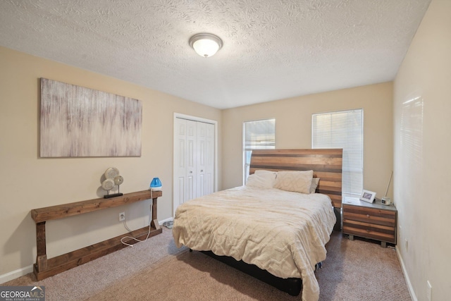 carpeted bedroom with a closet, a textured ceiling, and baseboards