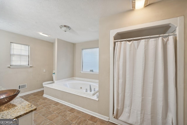 bathroom with visible vents, baseboards, a textured ceiling, and a whirlpool tub