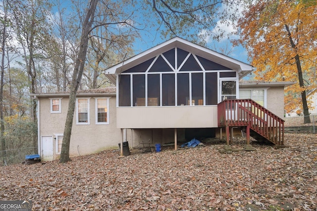 rear view of property with stairs, a sunroom, and stucco siding