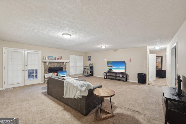 living area with a stone fireplace, french doors, carpet floors, and a textured ceiling