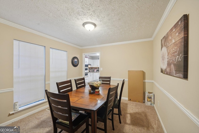 dining room with light colored carpet, a textured ceiling, crown molding, and baseboards