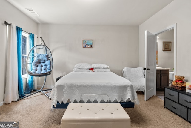 bedroom featuring visible vents, light colored carpet, ensuite bath, and baseboards