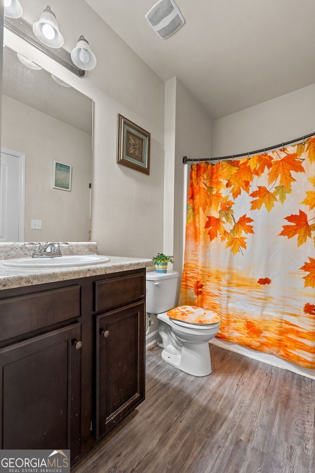 bathroom with vanity, toilet, wood finished floors, and visible vents