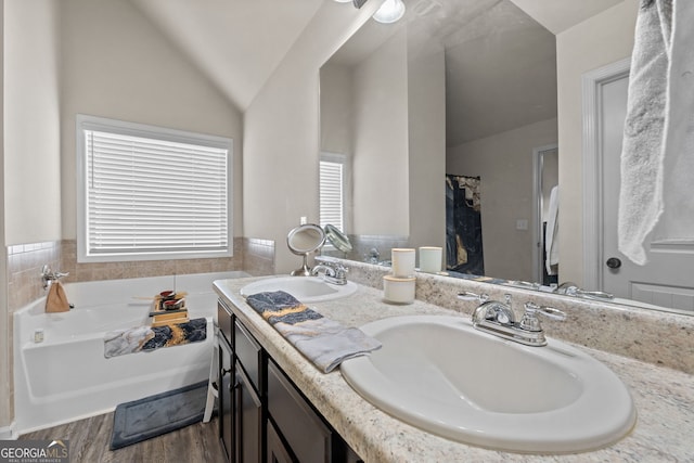 full bath with a bath, vaulted ceiling, wood finished floors, and a sink