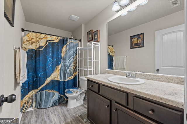 bathroom with visible vents, toilet, vanity, and wood finished floors