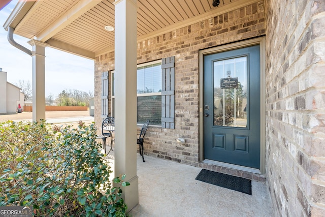 property entrance with brick siding and covered porch