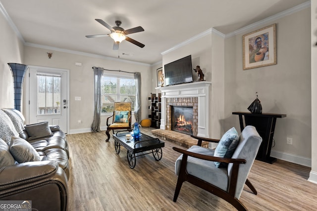 living area featuring baseboards, wood finished floors, a fireplace, and ornamental molding