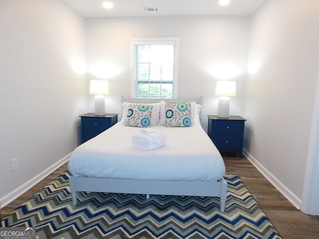 bedroom with dark wood-style floors, visible vents, and baseboards