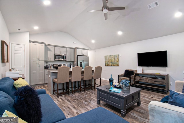 living area featuring vaulted ceiling, visible vents, a ceiling fan, and wood finished floors