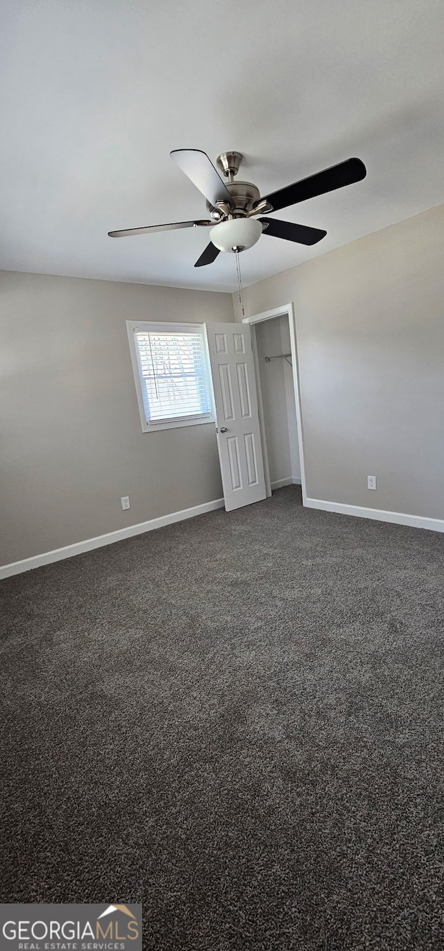 spare room featuring a ceiling fan, baseboards, and dark carpet