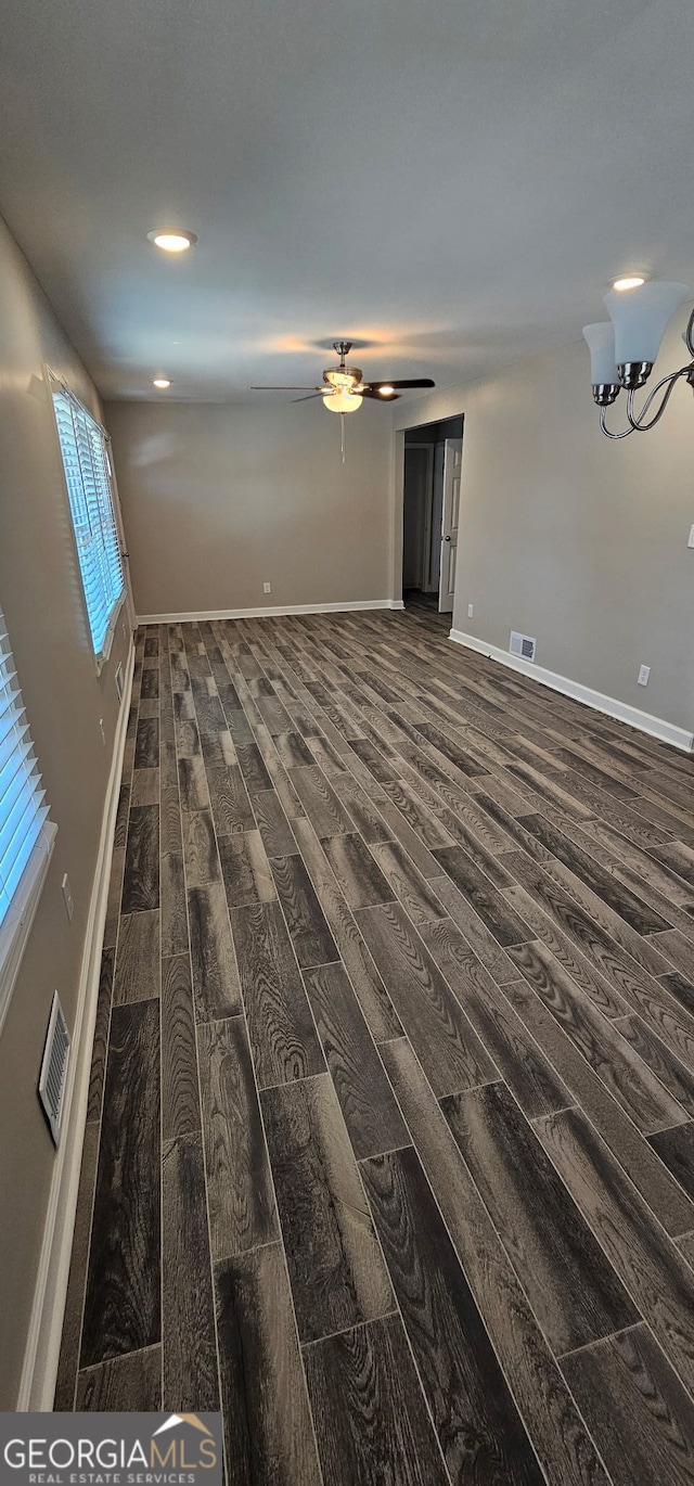 interior space with visible vents, baseboards, dark wood-style floors, and a ceiling fan