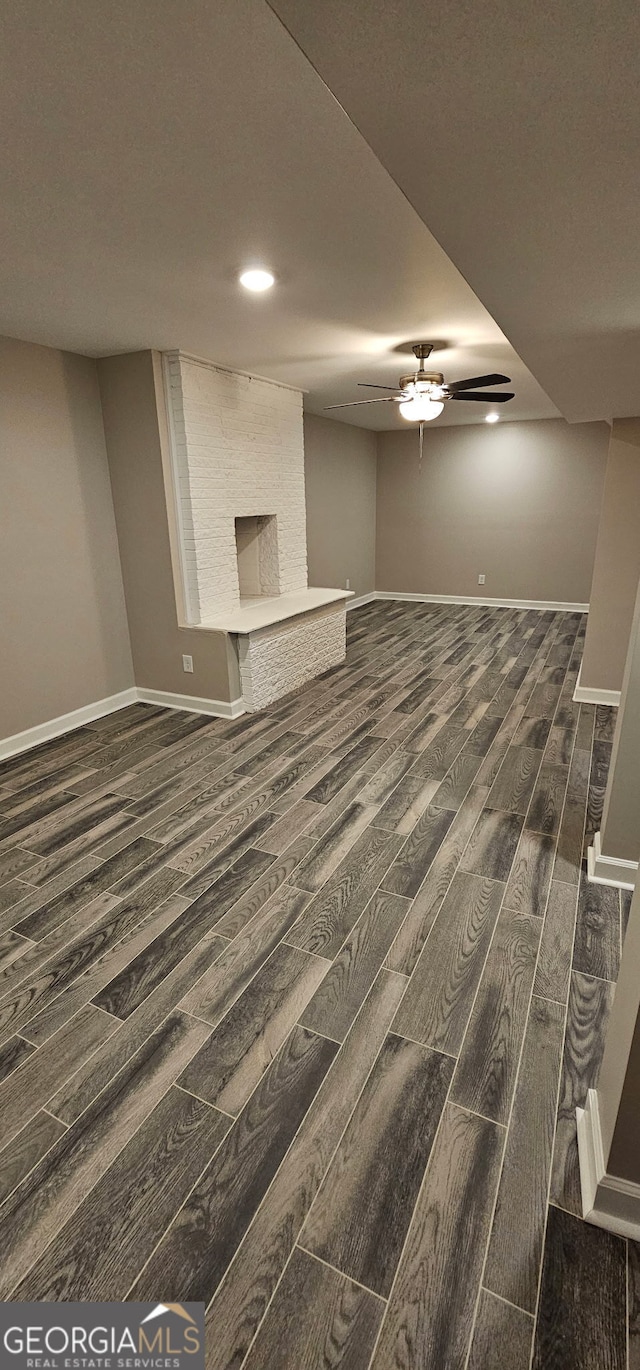 unfurnished living room featuring baseboards, dark wood-type flooring, and ceiling fan