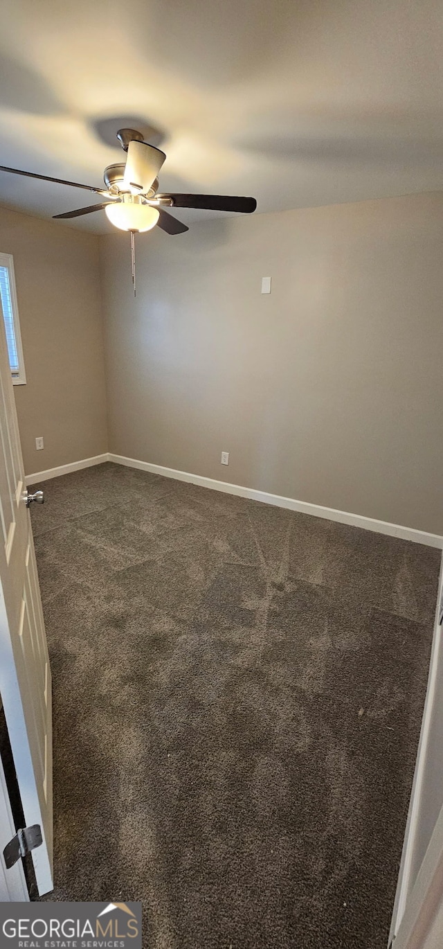 unfurnished room featuring baseboards, dark colored carpet, and ceiling fan