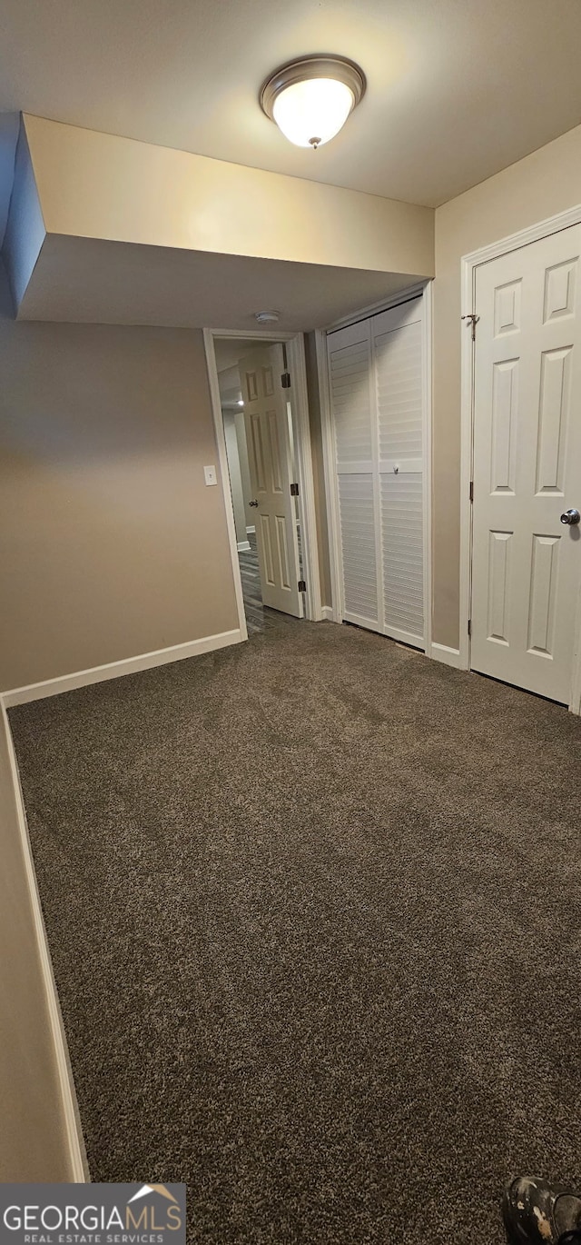 interior space featuring baseboards and dark carpet