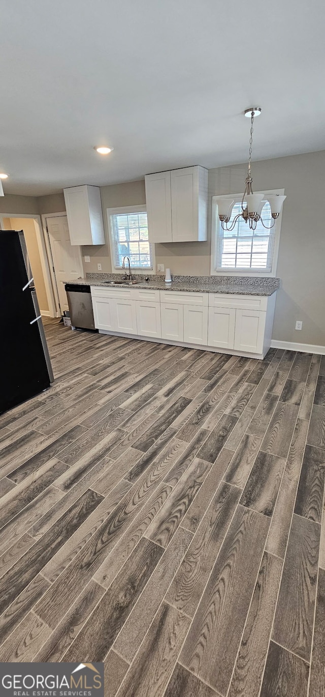 kitchen with dark wood-type flooring, freestanding refrigerator, white cabinets, baseboards, and a chandelier