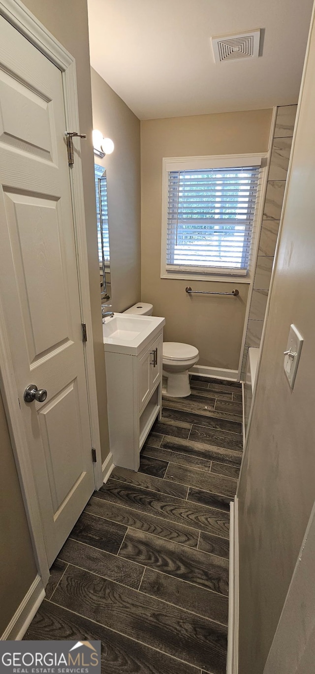 bathroom featuring vanity, toilet, visible vents, and wood finish floors