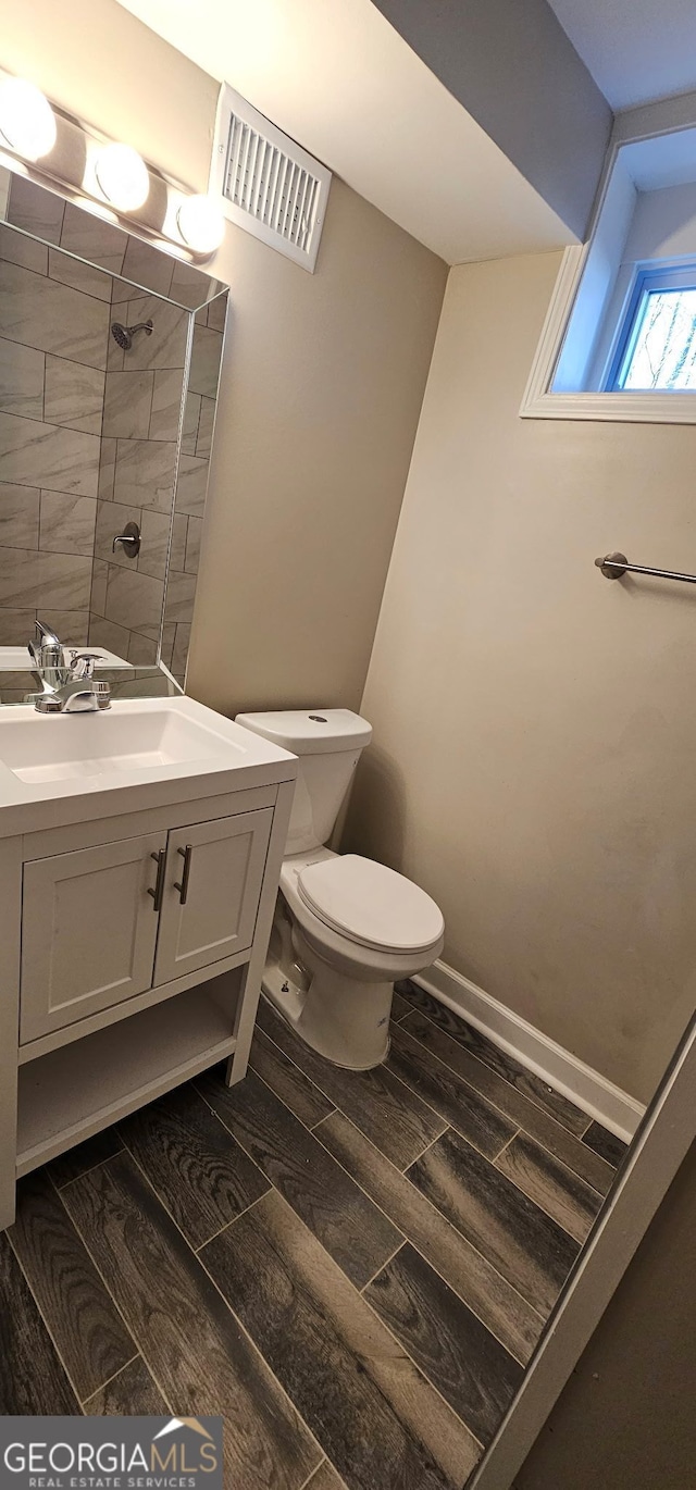 full bath featuring visible vents, toilet, a tile shower, vanity, and wood tiled floor