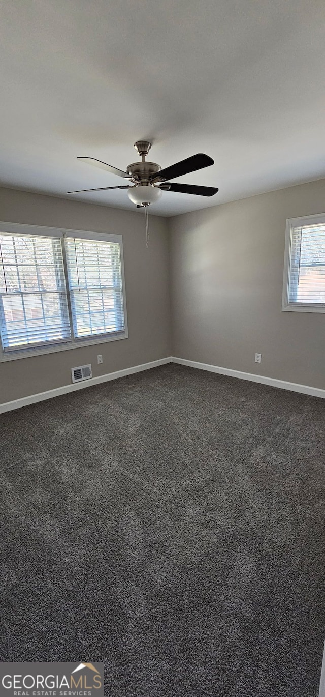 unfurnished room with a ceiling fan, baseboards, visible vents, and dark colored carpet