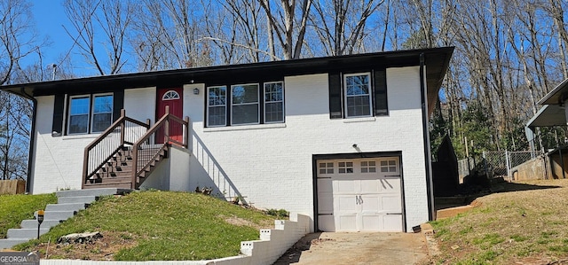 view of front of home with a garage, brick siding, concrete driveway, and fence