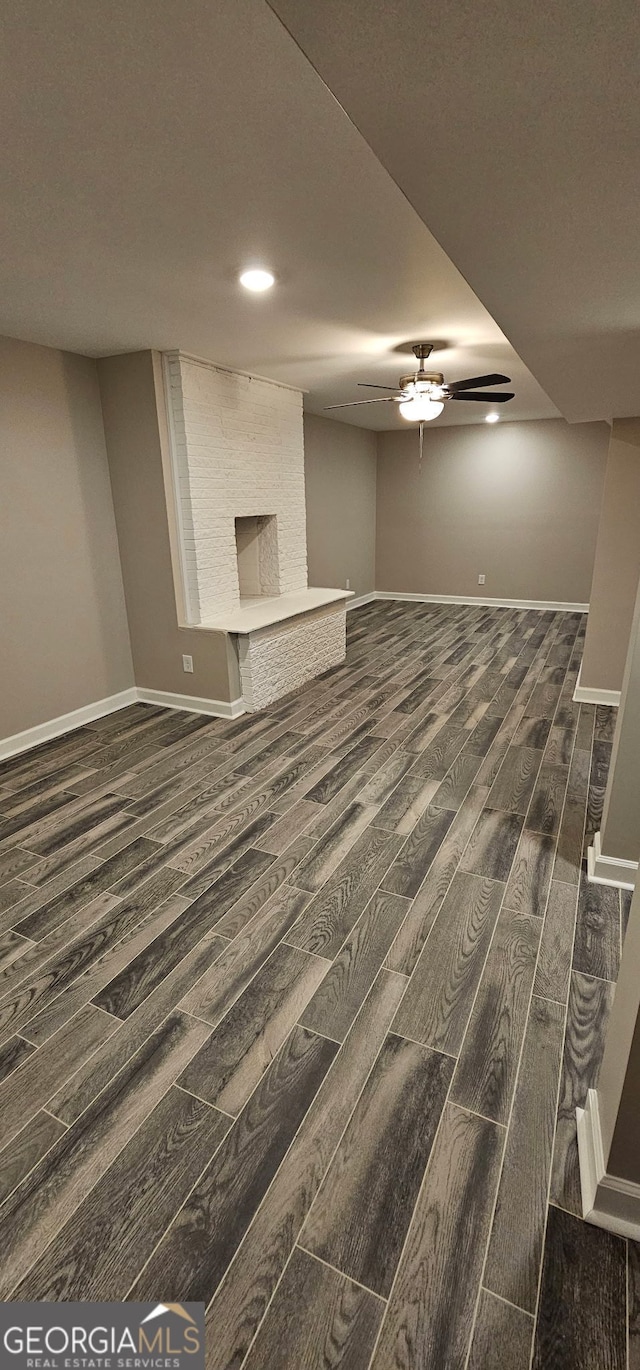 unfurnished living room featuring dark wood-style floors, ceiling fan, and baseboards