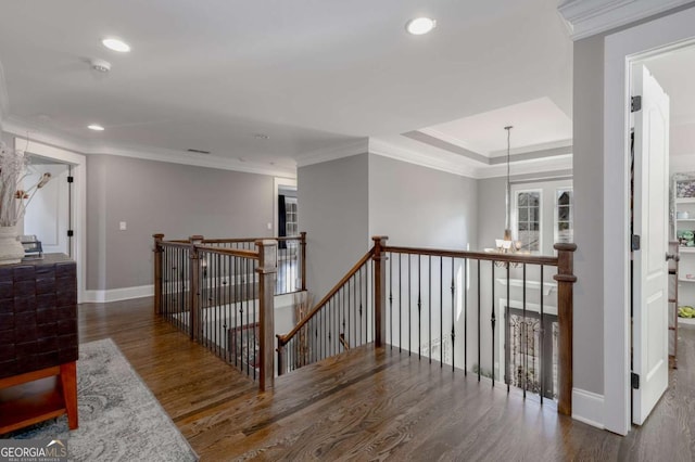 hallway featuring wood finished floors, baseboards, recessed lighting, crown molding, and an upstairs landing