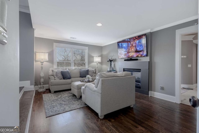 living room with dark wood-style floors, a glass covered fireplace, crown molding, and baseboards