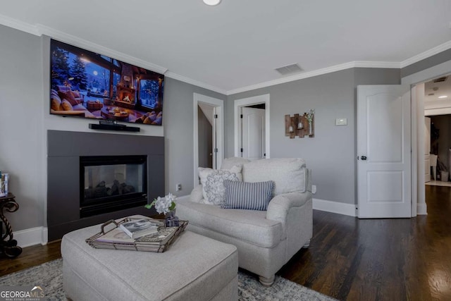 living room with visible vents, baseboards, wood finished floors, and crown molding