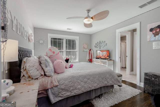 bedroom featuring baseboards, wood finished floors, visible vents, and ceiling fan