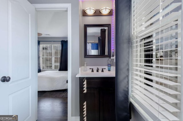 ensuite bathroom with ensuite bath, vanity, and wood finished floors