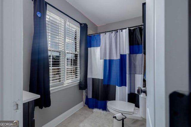 bathroom featuring a wealth of natural light, a shower with curtain, baseboards, and toilet