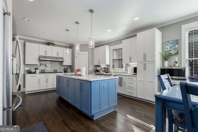 kitchen with ornamental molding, light countertops, white cabinets, appliances with stainless steel finishes, and blue cabinets