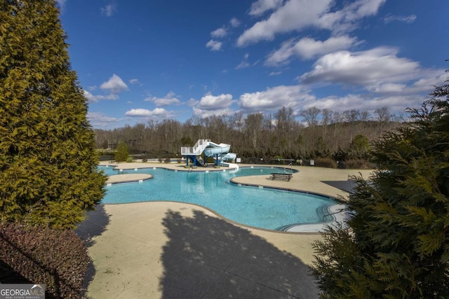 pool featuring a water slide and a patio area