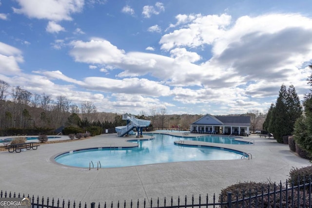 pool with a patio, fence, and a water slide