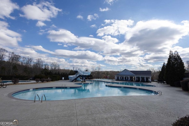 community pool featuring a patio area and a water slide