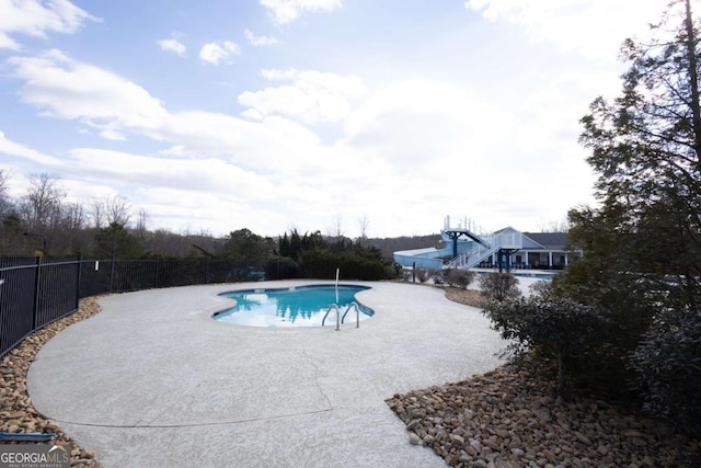 view of swimming pool with a fenced in pool, a water slide, a patio, and fence