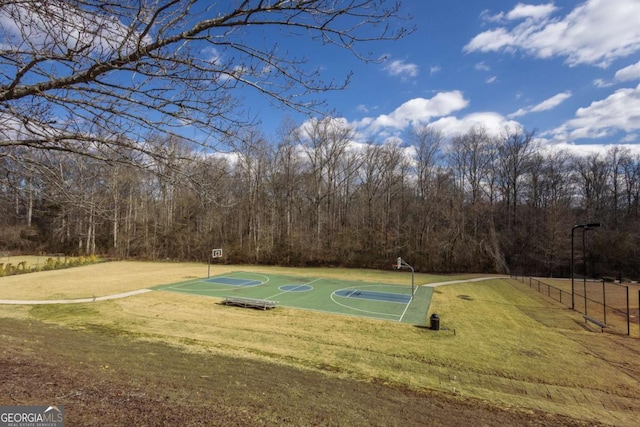 view of basketball court with community basketball court, a lawn, and fence