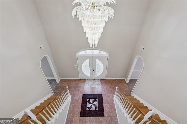 entryway featuring baseboards, a notable chandelier, and stairs