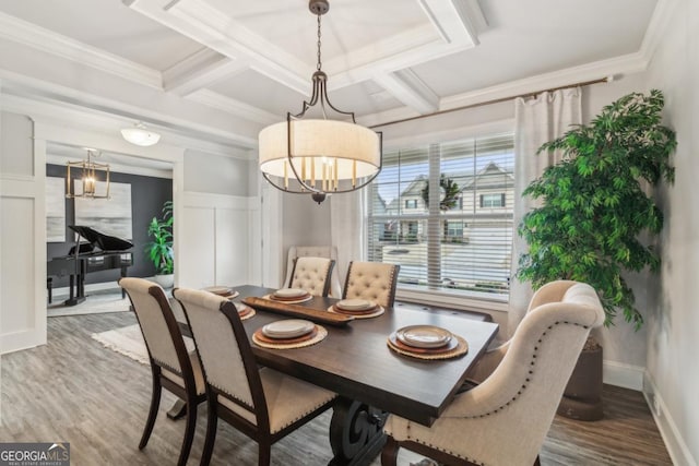 dining room with ornamental molding, coffered ceiling, wood finished floors, wainscoting, and a chandelier