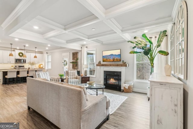 living room featuring a glass covered fireplace, beam ceiling, coffered ceiling, and wood finished floors