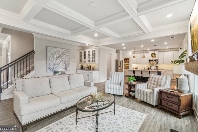 living area featuring beamed ceiling, coffered ceiling, and light wood finished floors